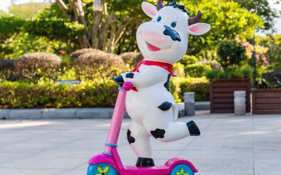 幼兒園卡通玻璃鋼彩繪騎滑板車的小奶牛雕塑